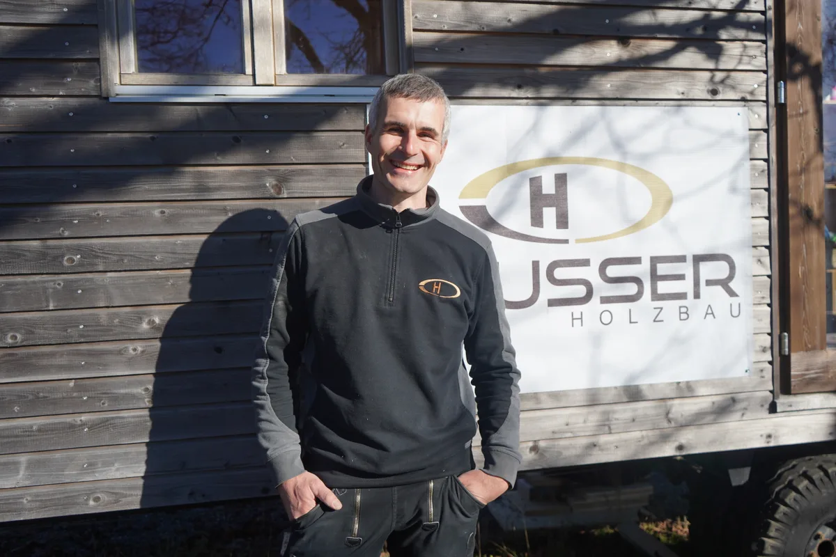 Florian Heusser lehnt an einem Bauwagen.